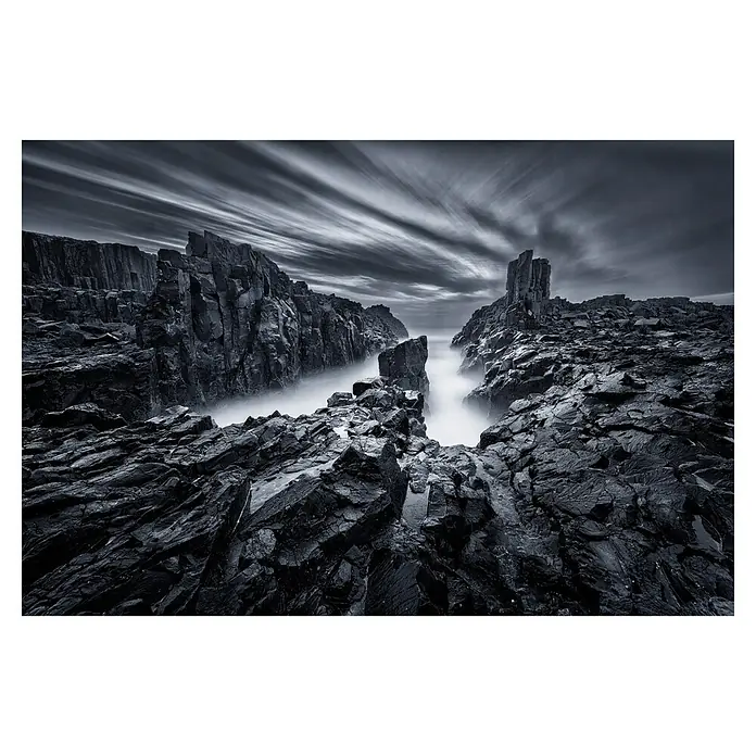 Papermoon Premium collection Fototapete Eisenwelt - B x H: 250 x 186 cm, Vlies - Dramatische Schwarzweißaufnahme von zerklüfteten Felsen am Meer unter einem bewegten Himmel, die die raue Schönheit der Natur hervorhebt.