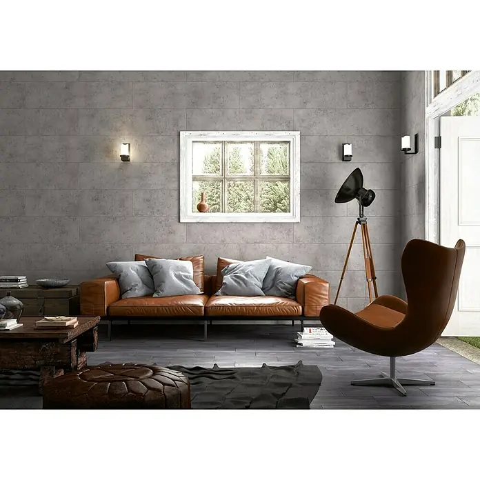 Bariperfil Perfil de acabado angular Concrete Oscuro - 2,6 m x 3 cm - Salón con sofá de cuero marrón, sillón y mesa de centro rústica sobre suelo de baldosas grises, acentuado por una vista de ventana y apliques de pared.