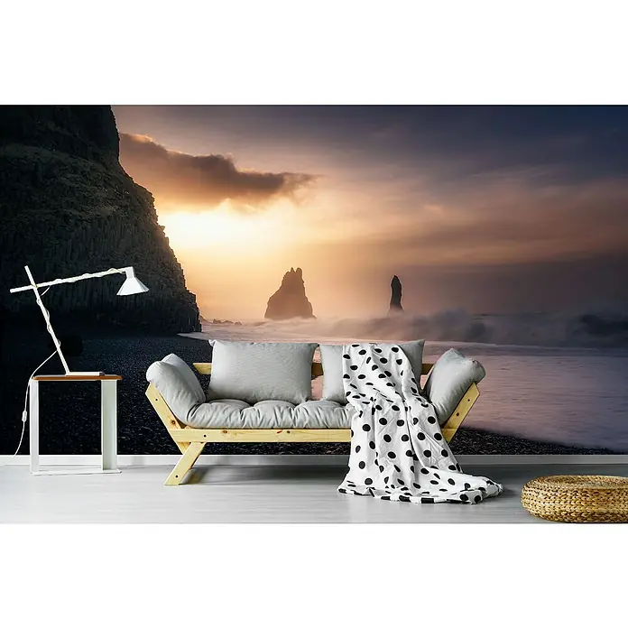 Papermoon Premium collection Fototapete Reynisfjara Sunrise - B x H: 400 x 260 cm, Vlies - Wandbild mit einem Sofa und einer Lampe vor einem Strand mit Felsen im Meer bei Sonnenuntergang.