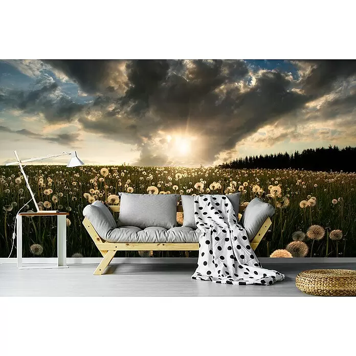 Papermoon Premium collection Fototapete Glühbirne - B x H: 250 x 186 cm, Vlies - Ein helles Holzsofa mit grauen Kissen, einer gepunkteten Decke, einer weißen Lampe und einem gewebten Pouf in einem Raum mit Löwenzahnfeld-Wand.