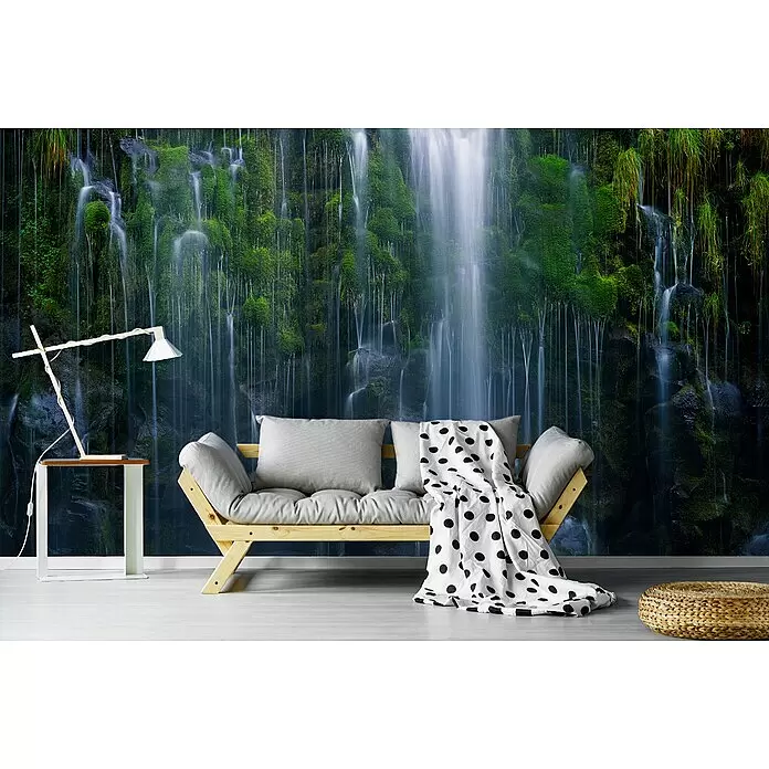 Papermoon Premium collection Fototapete Magischer Rückzug - B x H: 250 x 186 cm, Vlies - Ein Holzsofa mit grauen Kissen und einer gepunkteten Decke in einem Raum mit einem Wasserfall-Wandbild.
