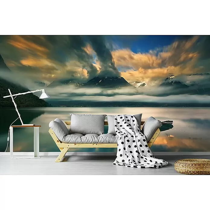 Papermoon Premium collection Fototapete Einer - B x H: 250 x 186 cm, Vlies - Holzsofa mit grauen Kissen & gepunkteter Decke, Beistelltisch mit Lampe und Strohpouf vor einem Berg-See-Wandbild.