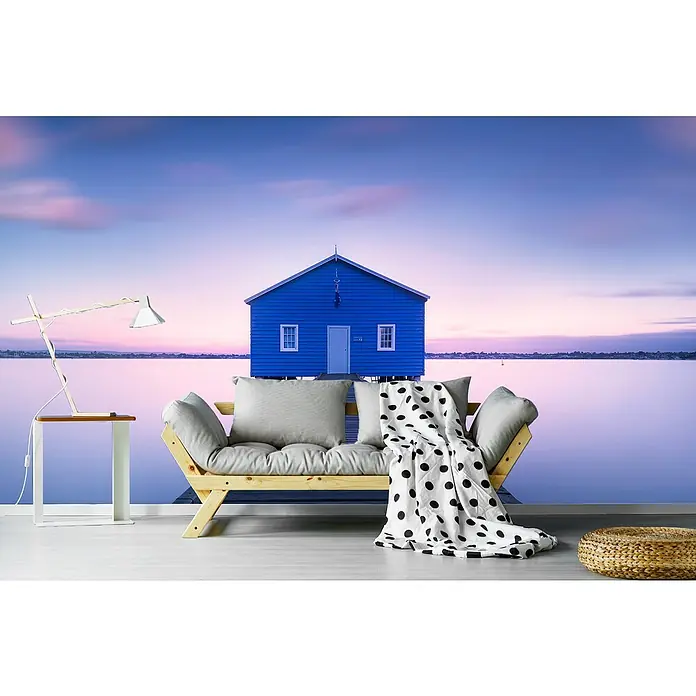 Papermoon Premium collection Fototapete Bootshaus - B x H: 450 x 280 cm, Vlies - Gemütliches Interieur mit einem hellen Holzbettsofa, hellgrauen Kissen und einer Decke mit Punkten. Ein Nachttisch mit Lampe steht daneben.