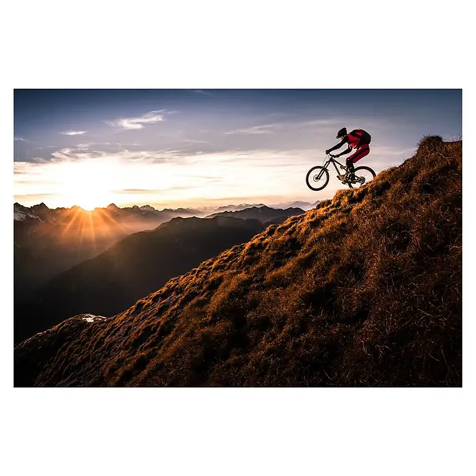 Papermoon Premium collection Fototapete Lebe das Abenteuer - B x H: 350 x 260 cm, Vlies - Mountainbiker springt bei Sonnenuntergang mit seinem Bike über einen Hügel, der mit Gras bewachsen ist. Action-Szene in den Bergen.