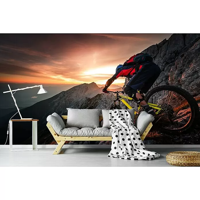 Papermoon Premium collection Fototapete Goldstunde Alpenfahrt BMX Fahrrad - B x H: 350 x 260 cm, Vlies - Eine Wandtapete mit einem Mountainbiker auf einem felsigen Gipfel bei Sonnenuntergang, die einen Raum mit Sofa und Lampe in eine dramatische Berglandschaft verwandelt.
