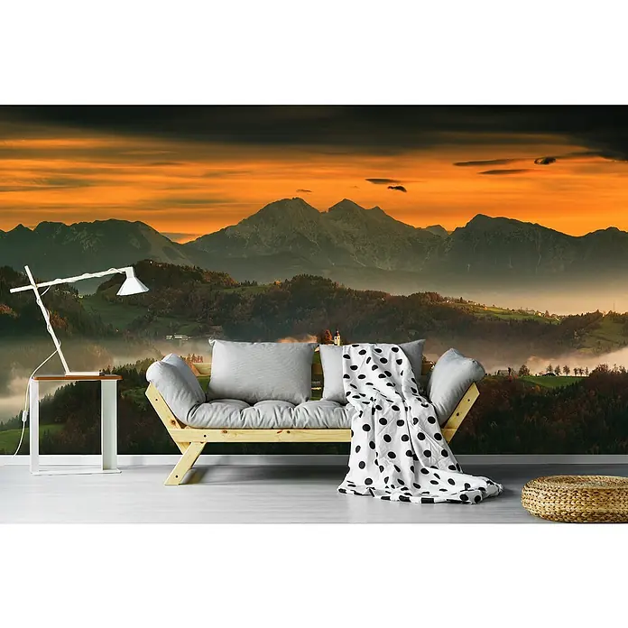 Papermoon Premium collection Fototapete Kirche - B x H: 400 x 260 cm, Vlies - Wandgemälde mit einer Szene von Bergen bei Sonnenuntergang hinter einem Sofa, einer Lampe und einem Ottomanen, die eine entspannende Atmosphäre schaffen.