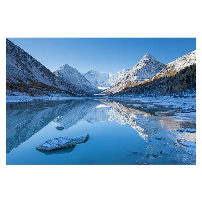 Papermoon Premium collection Fototapete Akkem See - B x H: 500 x 280 cm, Vlies - Winterliche Landschaft mit schneebedeckten Bergen, die sich in einem klaren See spiegeln. Ein großer Felsblock liegt im Vordergrund im eisigen Wasser.