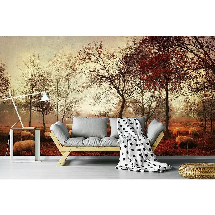 Papermoon Premium collection Fototapete Die letzten Tage des Herbstes - B x H: 450 x 280 cm, Vlies - Elegantes Wohnzimmer mit Sofa, Tischlampe und einem dekorativen Hocker vor einer Fototapete mit herbstlicher Waldszene und Schafen.