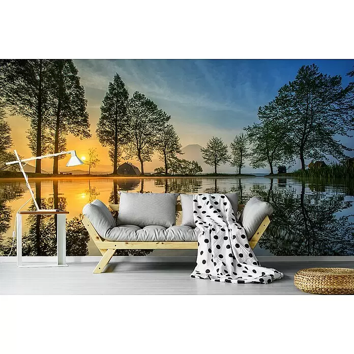 Papermoon Premium collection Fototapete Japan - B x H: 350 x 260 cm, Vlies - Ein Holzsofa mit grauen Kissen und Tupfendecke, ein weißer Beistelltisch mit Lampe und ein geflochtener Pouf in einem Raum mit Naturwandbild.