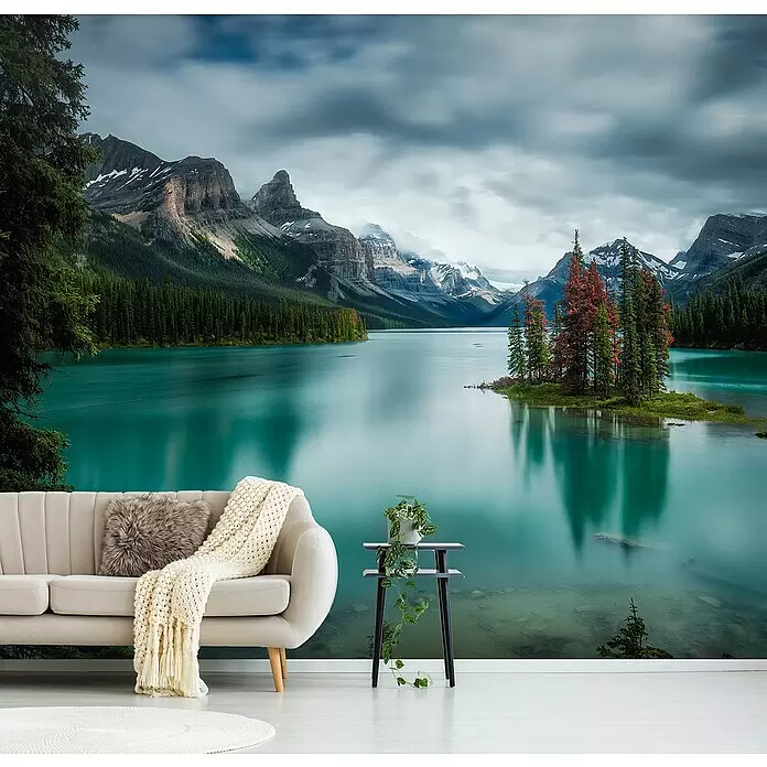 Papermoon Premium collection Fototapete Spirit Island - B x H: 500 x 280 cm, Vlies - Wandtapete mit einem türkisfarbenen Bergsee, Pinien und schneebedeckten Gipfeln, hinter einem hellen Sofa und Beistelltisch in einem Wohnzimmer.