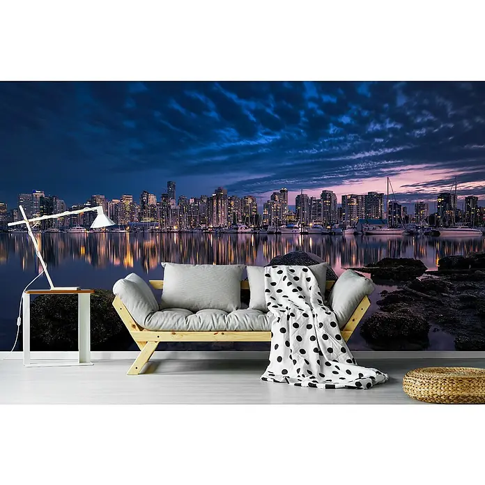 Papermoon Premium collection Fototapete Eine glühende Perle - B x H: 350 x 260 cm, Vlies - Wandbild mit einer nächtlichen Stadtsilhouette am Wasser, dekoriert mit Sofa, Lampe und Decke, schafft eine gemütliche Atmosphäre.
