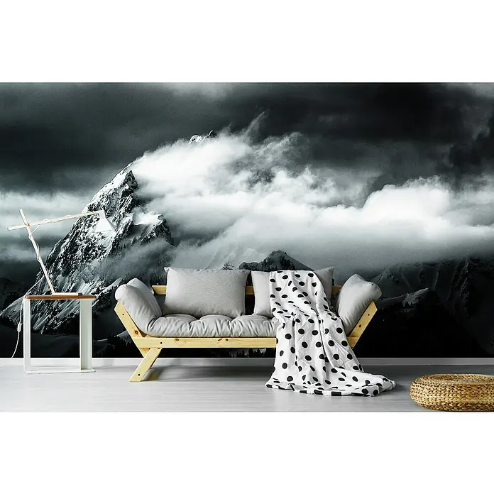 Papermoon Premium collection Fototapete Felsen und Wind - B x H: 300 x 223 cm, Vlies - Zimmer mit einer Holzliege, grauen Kissen und einer gepunkteten Decke vor einer Bergtapete.