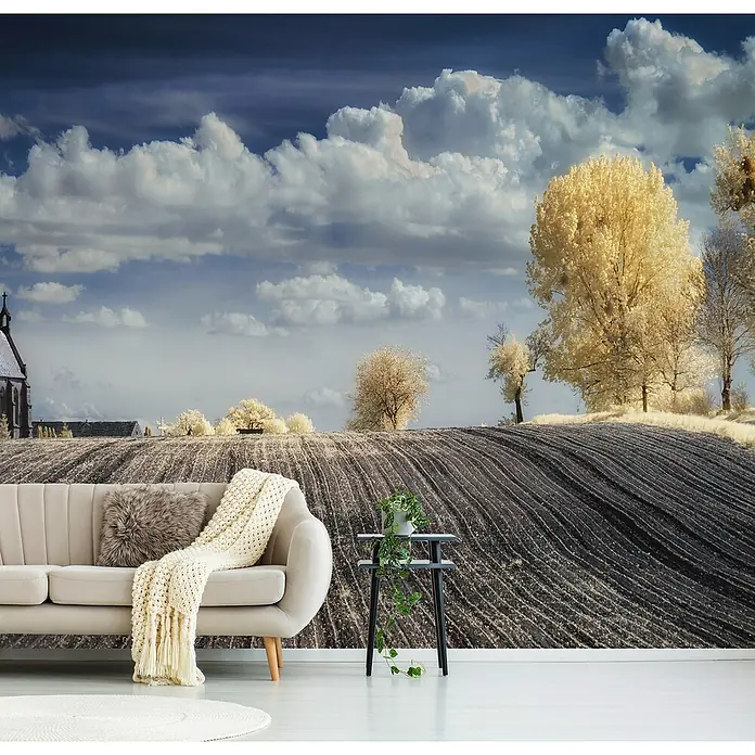 Papermoon Premium collection Fototapete Irenkowo - B x H: 400 x 260 cm, Vlies - Ein stilvolles Wohnzimmer mit einem beigen Sofa und einer malerischen Landschaftstapete mit Bäumen und Wolken.