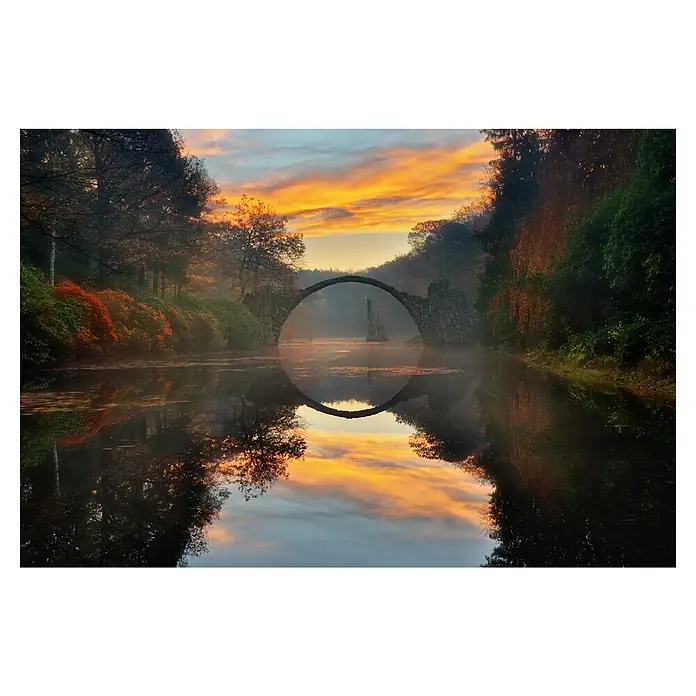 Papermoon Premium collection Fototapete Herbstgarten - B x H: 300 x 223 cm, Vlies - Atemberaubende Spiegelung der Rakotzbrücke im Wasser bei Sonnenaufgang, umgeben von üppiger Vegetation und einem farbenfrohen Himmel.