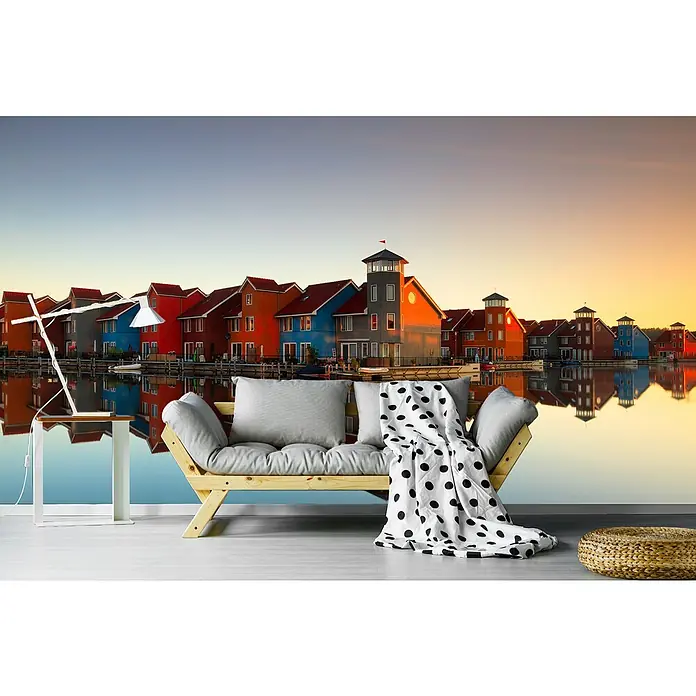Papermoon Premium collection Fototapete Buntes Dorf - B x H: 400 x 260 cm, Vlies - Ein stilvolles Interieur mit einer Couch, einer Lampe und bunten Häusern im Hintergrund, die sich im Wasser spiegeln.