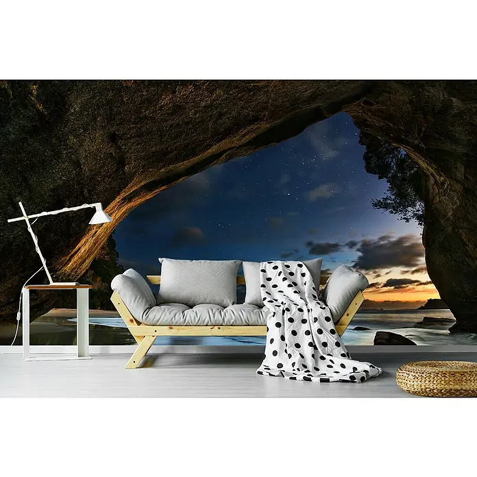 Papermoon Premium collection Fototapete Cathedral Cove - B x H: 250 x 186 cm, Vlies - Modernes Wohnzimmer mit einem Futon-Sofa, einer Stehlampe und einem gemütlichen Hocker. Das Sofa lädt mit Kissen und Decke zum Entspannen ein.