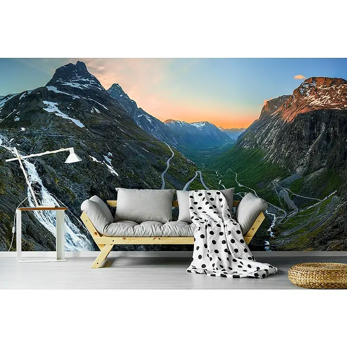 Papermoon Premium collection Fototapete Trollstigen - B x H: 500 x 280 cm, Vlies - Eine stilvolle Couch mit Kissen und einer Decke mit Punkten vor einer atemberaubenden Berglandschaft. Die Couch lädt zum Entspannen ein.