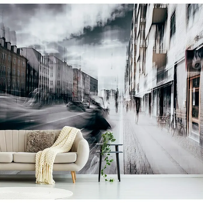 Papermoon Premium collection Fototapete Leben In Kopenhagen - B x H: 250 x 186 cm, Vlies - Das stilvolle Interieur präsentiert ein beiges Sofa mit Kissen und Decke vor einer Wandtapete mit Stadtmotiv, ergänzt durch einen Beistelltisch mit Pflanze.