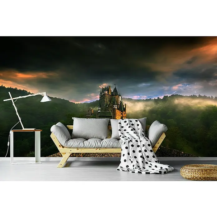 Papermoon Premium collection Fototapete Eltz II - B x H: 200 x 149 cm, Vlies - Wandbild mit einer Burg im Hintergrund, einer Lampe und einer Couch mit Decke im Vordergrund für eine gemütliche Atmosphäre.