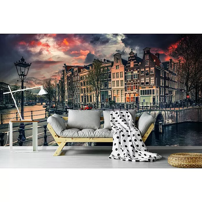 Papermoon Premium collection Fototapete Brücke in Amsterdam - B x H: 350 x 260 cm, Vlies - Ein Holzsofa mit hellgrauen Kissen und einer weißen Tupfendecke vor einem Wandbild mit Kanalmotiv.