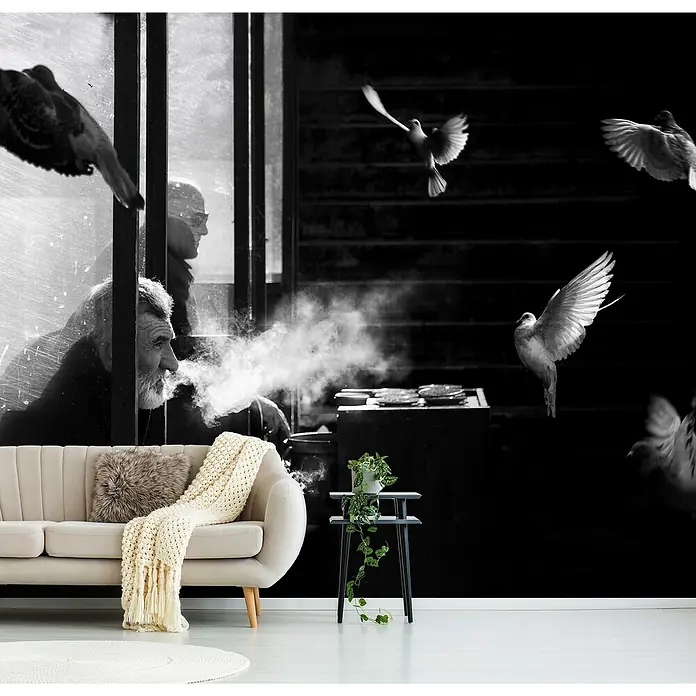 Papermoon Premium collection Fototapete Der Mann der Tauben - B x H: 500 x 280 cm, Vlies - Wohnzimmer mit beigem Sofa, Kissen und Decke vor einer eindrucksvollen Schwarz-Weiß-Fototapete mit Mann, Rauch und Tauben.