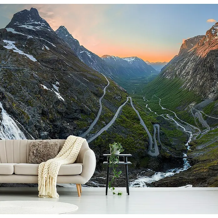 Papermoon Premium collection Fototapete Trollstigen - B x H: 500 x 280 cm, Vlies - Eine elegante Couch mit Decke vor einer beeindruckenden Berglandschaft-Fototapete. Ideal für stilvolle Wohnräume.