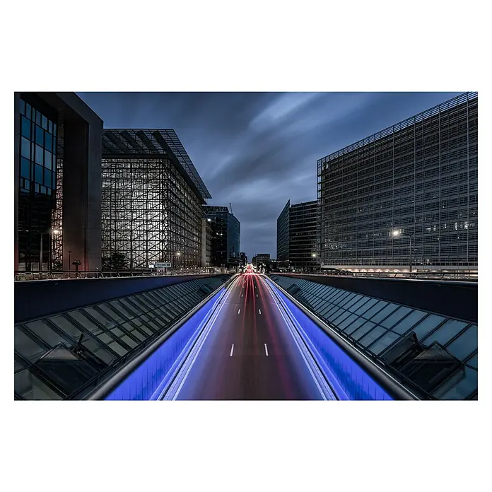 Papermoon Premium collection Fototapete Brüssel Nacht - B x H: 350 x 260 cm, Vlies - Blick auf eine nächtliche Straße, flankiert von modernen Bürogebäuden und blauen Lichtern, die eine futuristische Atmosphäre schaffen.