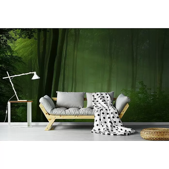 Papermoon Premium collection Fototapete Waldmorgen - B x H: 250 x 186 cm, Vlies - Holzsofa mit grauen Kissen und einer weiß-gepunkteten Decke, daneben eine weiße Lampe auf einem Beistelltisch und ein gewebter Pouf.