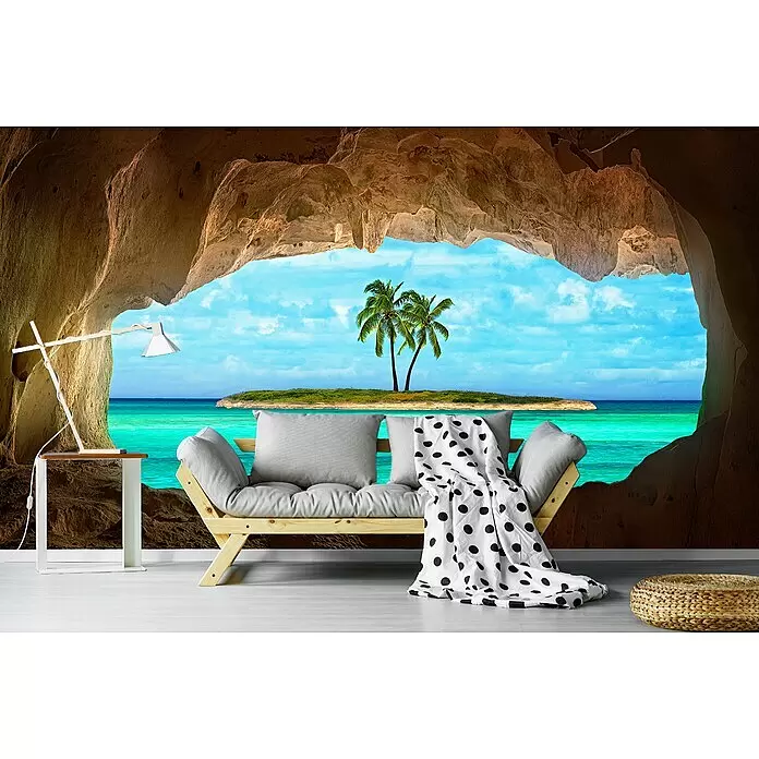 Papermoon Premium collection Fototapete Paradies - B x H: 250 x 186 cm, Vlies - Ein Futonsofa aus Holz mit hellgrauen Kissen und gepunkteter Decke in einem Höhlenzimmer mit Blick auf ein tropisches Meer.