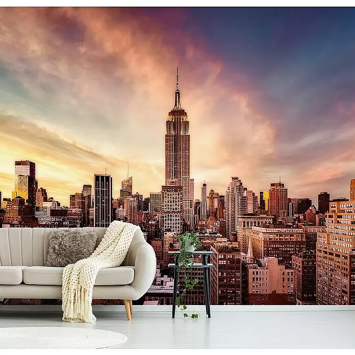 Papermoon Premium collection Fototapete Midtown Sunset - B x H: 350 x 260 cm, Vlies - Wandbild mit New Yorker Skyline bei Sonnenuntergang, installiert in einem Raum mit beigem Sofa und einer kleinen Pflanze.