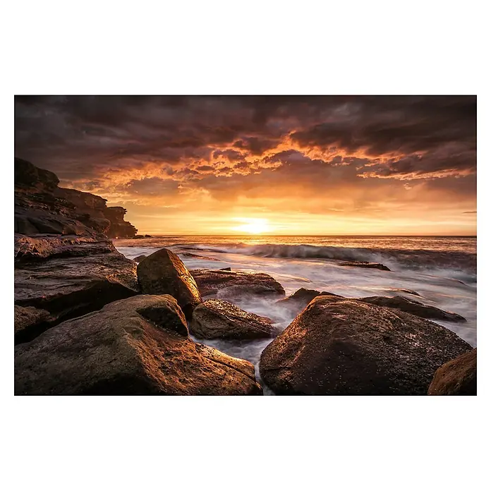Papermoon Premium collection Fototapete Kapslöcher - B x H: 500 x 280 cm, Vlies - Sonnenuntergang über dem Meer, Wellen umspülen die Felsenküste, der Himmel in warmen Orange- und Rottönen getaucht, idyllische Küstenlandschaft.