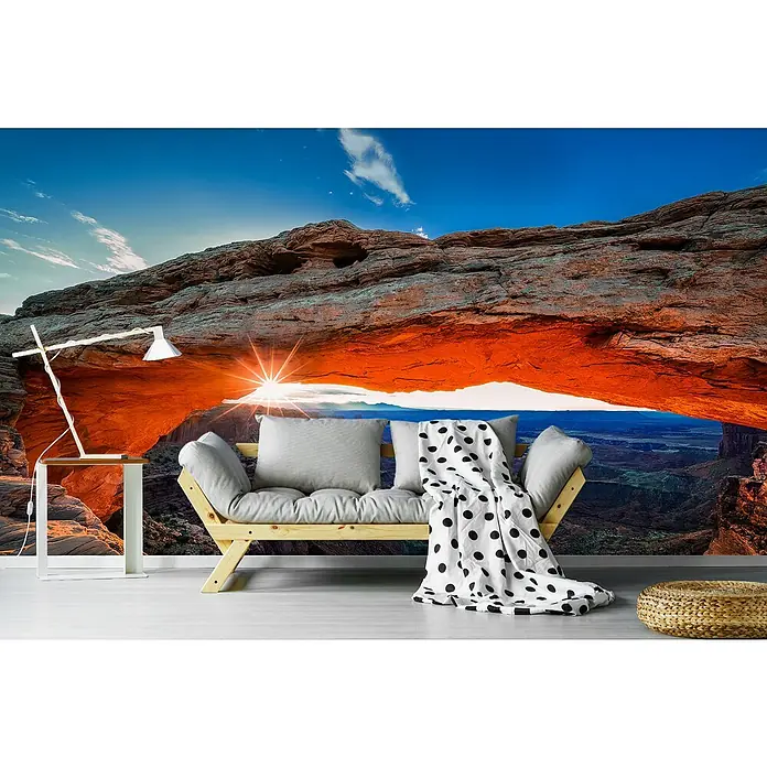 Papermoon Premium collection Fototapete Sunrise Mesa-Bogen - B x H: 350 x 260 cm, Vlies - Wandbild mit Felsbogen-Motiv, ergänzt durch eine gemütliche Couch mit Decke und Kissen, die einladend wirkt.