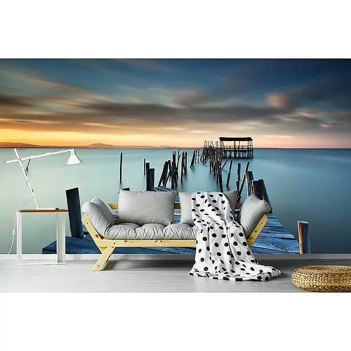 Papermoon Premium collection Fototapete Zusammengebrochen - B x H: 400 x 260 cm, Vlies - Wandtapete mit ruhigem Sonnenuntergang über einem Pier und Meer, ergänzt ein modernes Wohnzimmer.