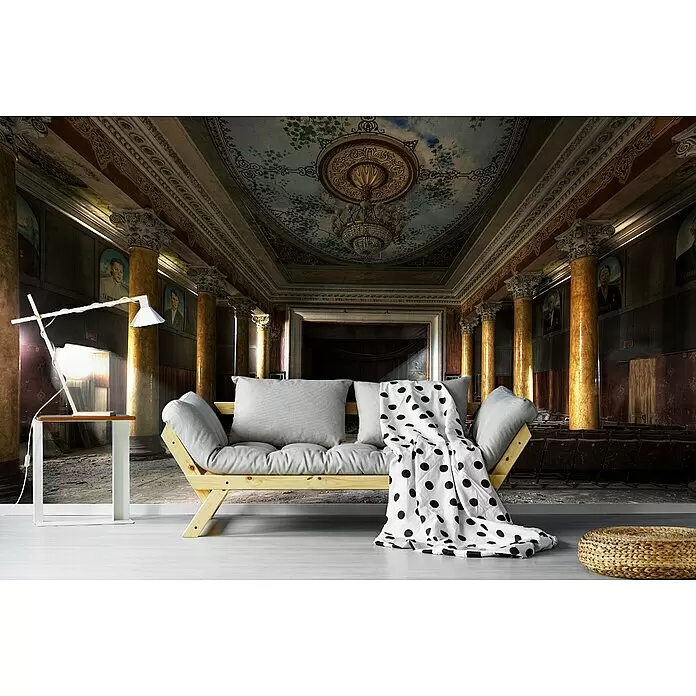 Papermoon Premium collection Fototapete Früherer Glanz - B x H: 300 x 223 cm, Vlies - Modernes helles Holzsofa mit grauen Kissen und gepunkteter Decke, weißem Beistelltisch mit Lampe und geflochtenem Pouf in einer verzierten Halle.