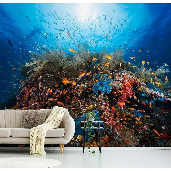 Papermoon Premium collection Fototapete Apnoe - B x H: 300 x 223 cm, Vlies - Wohnzimmer mit Korallenriff-Fototapete, die eine lebendige Unterwasserwelt zeigt. Bequemes Sofa und minimalistischer Beistelltisch ergänzen das lebhafte Wandbild.