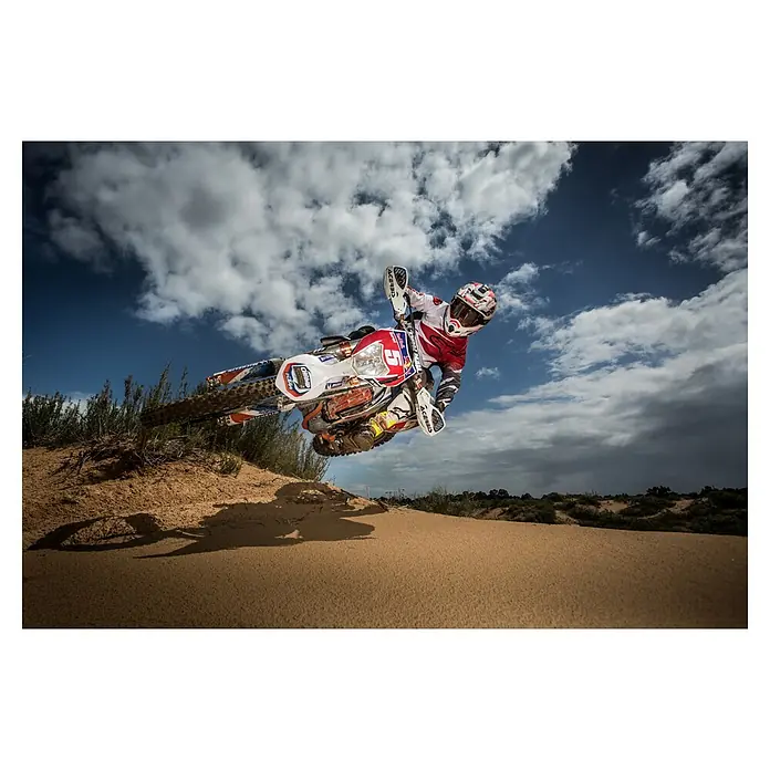 Papermoon Premium collection Fototapete Motorradaction in der Wüste - B x H: 450 x 280 cm, Vlies - Ein Motocross-Fahrer in der Luft auf einem KTM-Motorrad, springend über Sanddünen unter einem bewölkten Himmel, wobei die Ausrüstung und das Bike im Fokus stehen.