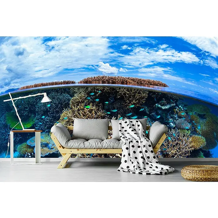 Papermoon Premium collection Fototapete Split Level Korallenriff - B x H: 350 x 260 cm, Vlies - Nahaufnahme eines Raumes mit einer Couch, einer Lampe und einem Hocker vor einer fotorealistischen Korallenrifftapete.