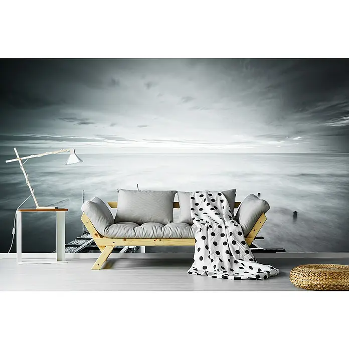 Papermoon Premium collection Fototapete In Unendlichkeit - B x H: 200 x 149 cm, Vlies - Ein modernes Interieur mit einem hellen Holzbettsofa, grauen Kissen, einer Lampe, einem Hocker und einer Decke mit schwarzen Punkten.