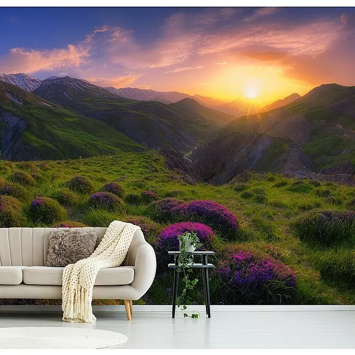 Papermoon Premium collection Fototapete Frühling in Show - B x H: 500 x 280 cm, Vlies - Eine Wandtapete zeigt eine lebendige Berglandschaft bei Sonnenuntergang und verwandelt ein Wohnzimmer mit grünen Hügeln und lila Blumen.