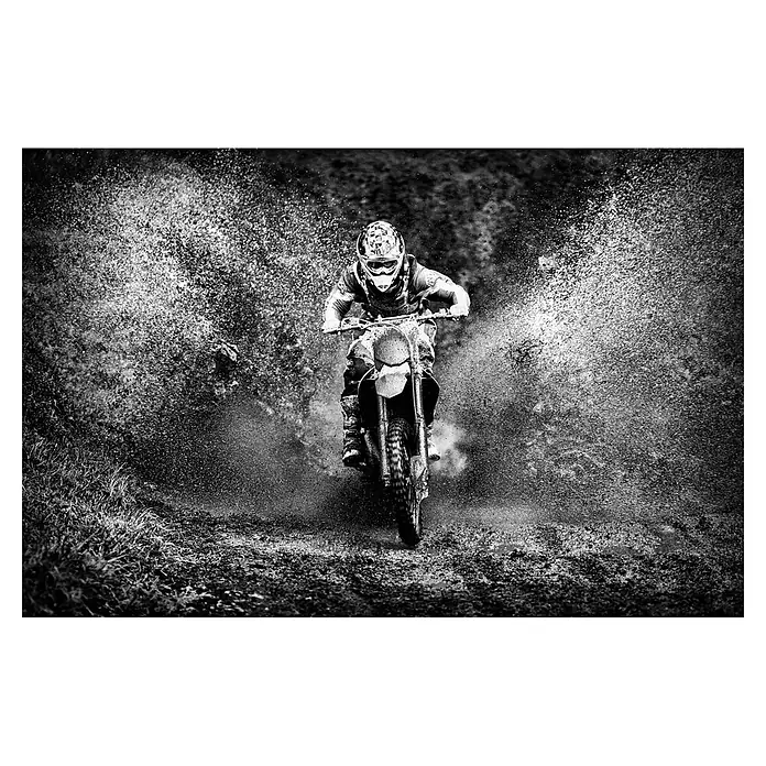 Papermoon Premium collection Fototapete Motorcross - B x H: 450 x 280 cm, Vlies - Schwarz-Weiß-Aufnahme eines Motocrossfahrers, der mit seinem Motorrad durch schlammiges Gelände fährt und dabei viel Schmutz aufwirbelt.
