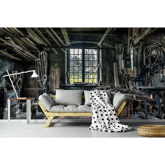 Papermoon Premium collection Fototapete Tischlerwerkstatt - B x H: 300 x 223 cm, Vlies - Holzsofa mit hellgrauen Kissen und gepunkteter Decke in rustikaler Werkstattumgebung.