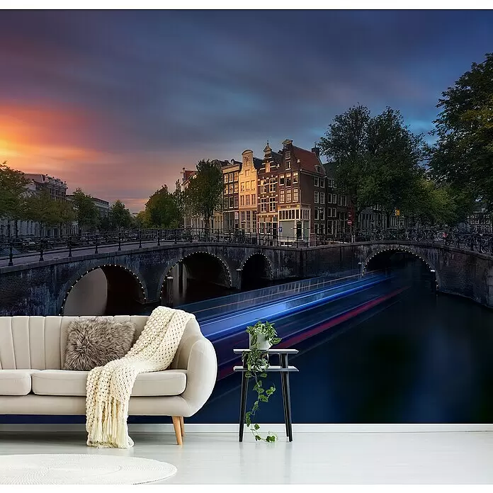Papermoon Premium collection Fototapete Amsterdam Sunset - B x H: 500 x 280 cm, Vlies - Großformatige Wandtapete eines Amsterdamer Kanals bei Sonnenuntergang mit Lichtspuren von Booten, als Kulisse hinter Sofa und Beistelltisch.