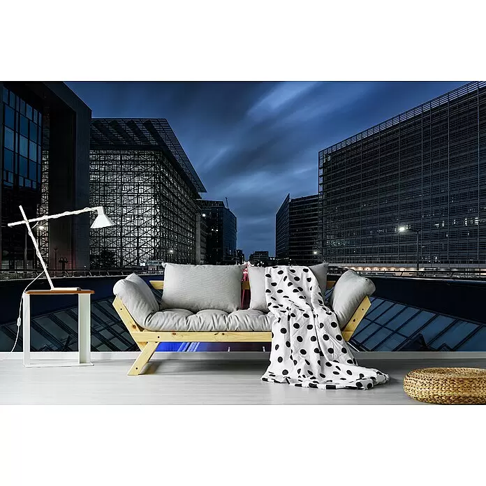 Papermoon Premium collection Fototapete Brüssel Nacht - B x H: 350 x 260 cm, Vlies - Holzsofa mit hellgrauen Kissen, weißer Decke mit schwarzen Punkten, Beistelltisch mit Lampe und Strohpouf.