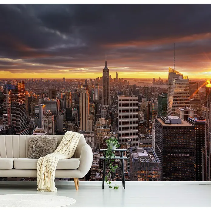 Papermoon Premium collection Fototapete Oben - B x H: 300 x 223 cm, Vlies - Wandbild mit New Yorker Skyline bei Sonnenuntergang hinter einem stilvollen Sofa und Beistelltisch.