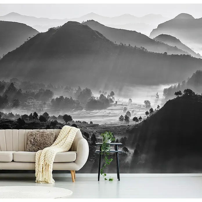 Papermoon Premium collection Fototapete Nebliges Meer von Wolken - B x H: 350 x 260 cm, Vlies - Elegante Inneneinrichtung mit einer stilvollen Couch, einem Beistelltisch mit Pflanze und einer beeindruckenden Berglandschaft im Hintergrund.