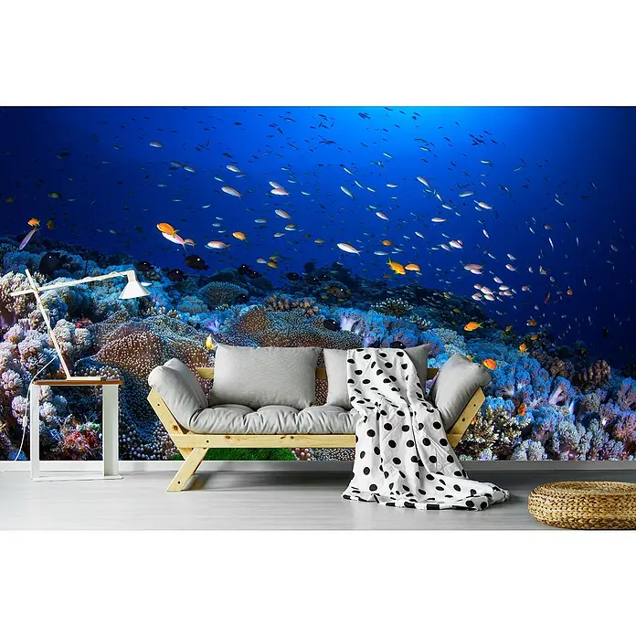 Papermoon Premium collection Fototapete Anemon und Anthias - B x H: 400 x 260 cm, Vlies - Einladendes Interieur mit einem Wandbild von Fischen und Korallenriff, das eine entspannende Atmosphäre schafft, ergänzt durch eine moderne Couch und Beistelltisch.