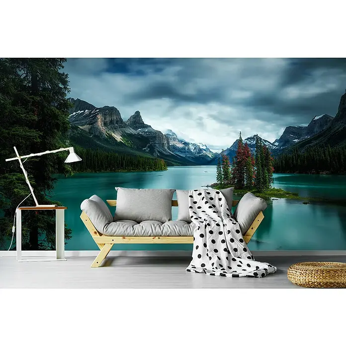 Papermoon Premium collection Fototapete Spirit Island - B x H: 500 x 280 cm, Vlies - Das Bild zeigt eine stilvolle Couch mit Kissen und Decke vor einer atemberaubenden Bergsee-Tapete, ergänzt durch eine moderne Lampe und einen Hocker.