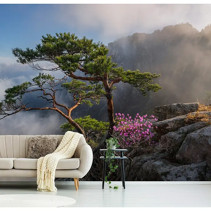 Papermoon Premium collection Fototapete Traumtänzerin - B x H: 200 x 149 cm, Vlies - Dieses Bild zeigt eine stilvolle Inneneinrichtung mit einer Naturtapete, die einen ruhigen Bergwald mit einem eleganten beigen Sofa kombiniert.