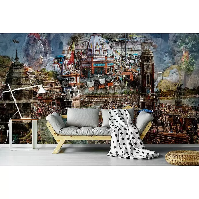 Papermoon Premium collection Fototapete Heiliges Indien - B x H: 250 x 186 cm, Vlies - Graues Holz-Futonsofa, weißer Beistelltisch mit Lampe, gepunktete Decke und gewebter Pouf in einem Raum mit Wandbild.