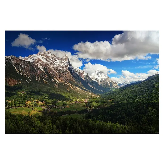 Papermoon Premium collection Fototapete Un-Valle - B x H: 400 x 260 cm, Vlies - Blick auf ein malerisches Tal mit schneebedeckten Bergen, üppigen Wäldern und einer charmanten Siedlung unter blauem Himmel mit Wolken.